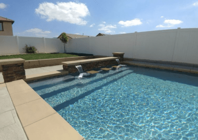 A backyard with a pool and a water feature.